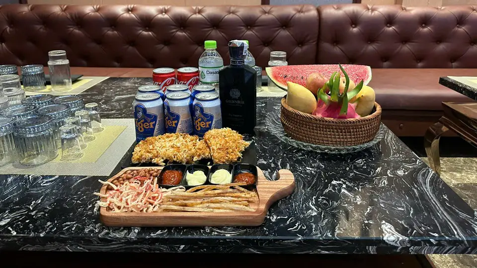 타이거 맥주, 골든블루 양주, 과일 바구니, 튀김 안주가 대리석 테이블 위에 세팅된 모습