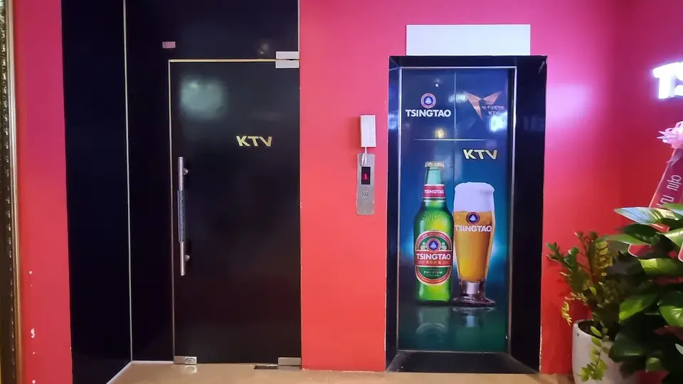 핑크 벽면과 KTV 전용 블랙 도어, 칭따오 맥주 광고 디스플레이가 설치된 가라오케 입구