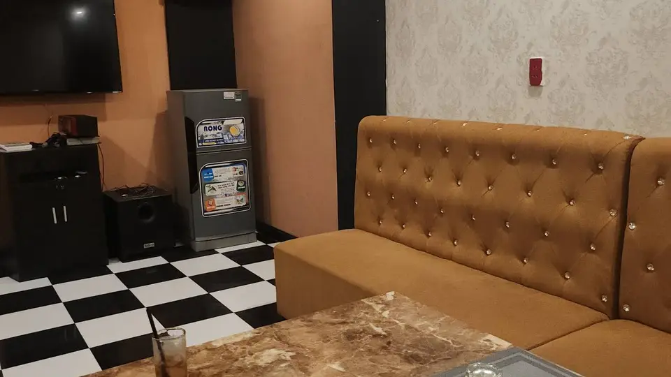 캐러멜 색상 버튼 소파와 소형 냉장고, TV가 구비된 아늑한 소형 가라오케 룸 내부
