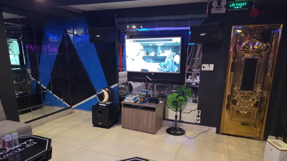 블랙 미러 패널과 대형 LED TV, 골드 프레임 장식 도어가 설치된 업타운 가라오케 개인 룸 내부