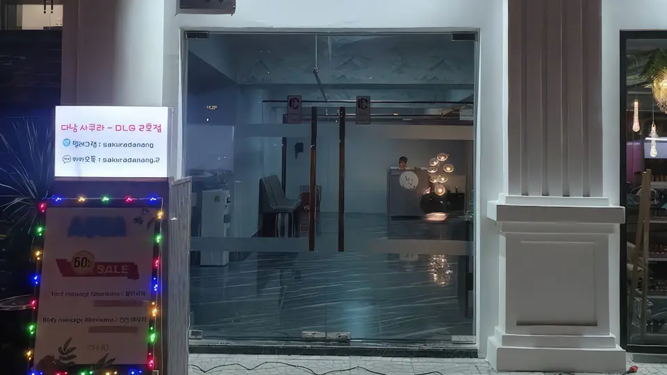 다낭 DLG 사쿠라 2호점 마사지 샵의 유리 외관과 네온 간판, 50% 세일 배너가 설치된 전경