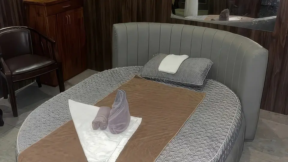고급 그레이 원형 마사지 베드와 정돈된 수건이 배치된 룸 내부