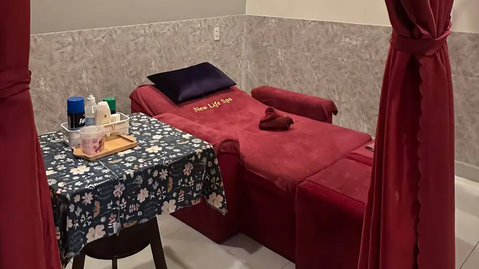 레드 커버의 마사지 베드와 네이비 쿠션, 아로마 오일 및 관리 용품이 갖춰진 1인 전용 룸