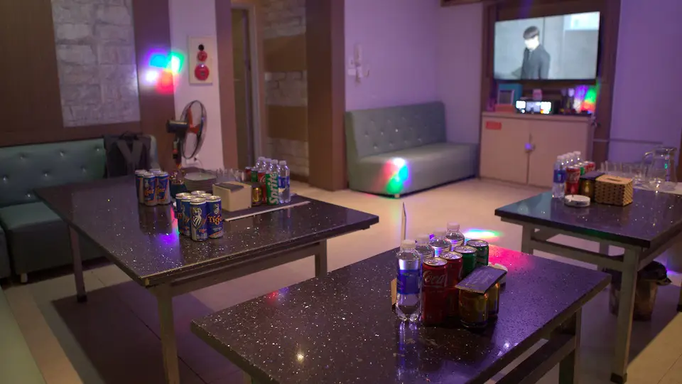 보라색 간접 조명과 RGB 파티 라이트, 화강암 테이블에 음료가 세팅된 박카스 가라오케의 스탠다드 룸 내부