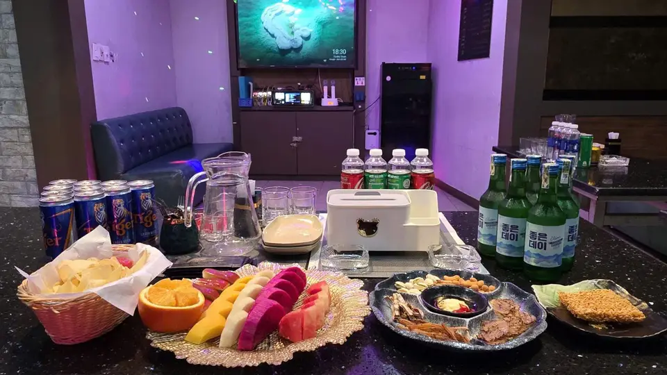 과일 모둠과 안주 플레이트, 소주병 및 음료수가 화강암 테이블에 가득 차려진 프리미엄 룸 세팅
