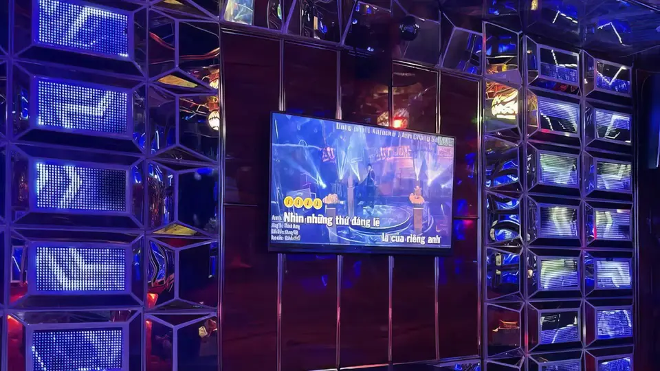 블루 LED 조명 큐브 패널과 크롬 미러 프레임 벽면, 대형 노래방 스크린이 설치된 하이테크 룸 전경