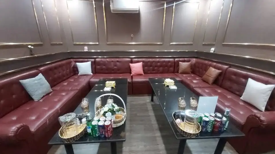킹덤 가라오케의 넓은 U자형 레드 가죽 소파와 블랙 대리석 테이블, 고급 음료 세팅이 완비된 VIP 라운지 룸
