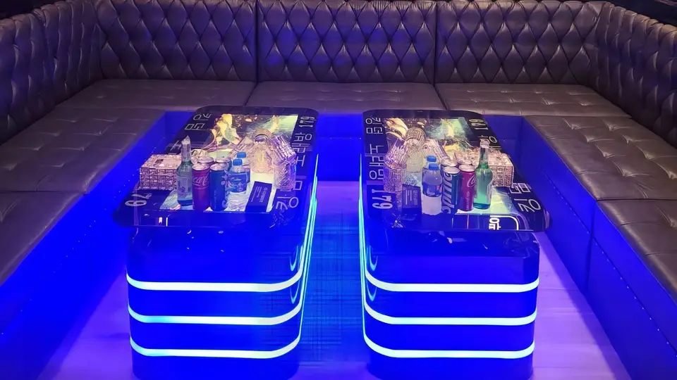 강렬한 블루 LED 빛이 반사되는 발광 테이블 2개와 다크 터프티드 가죽 소파가 배치된 룸
