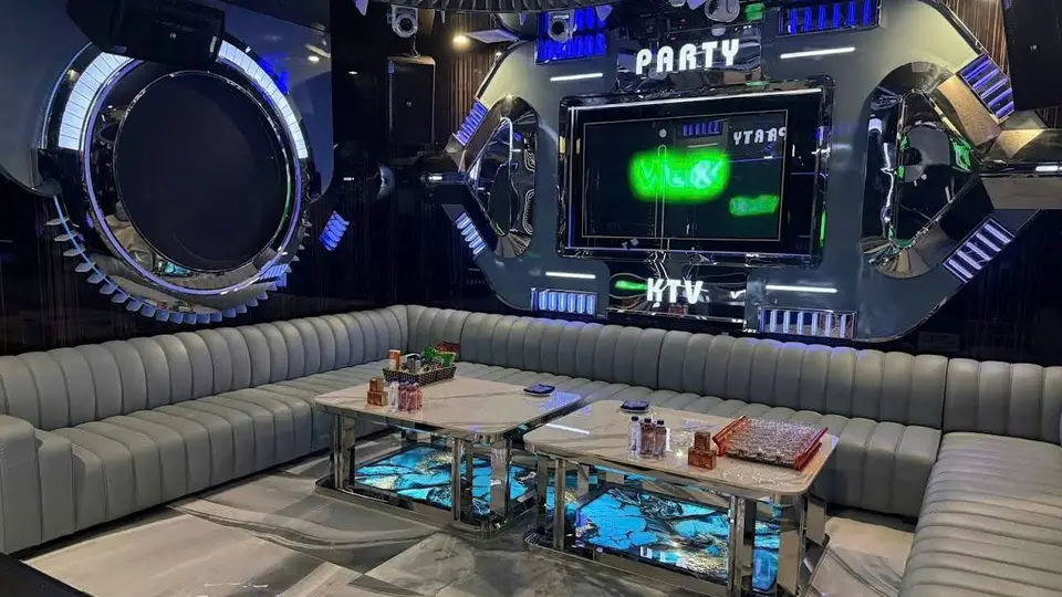 크롬 원형 프레임 스테이지와 PARTY·KTV 네온 사인, 그레이 채널 소파 및 마블 패턴 LED 내장 테이블이 갖춰진 스페이스 파티 룸