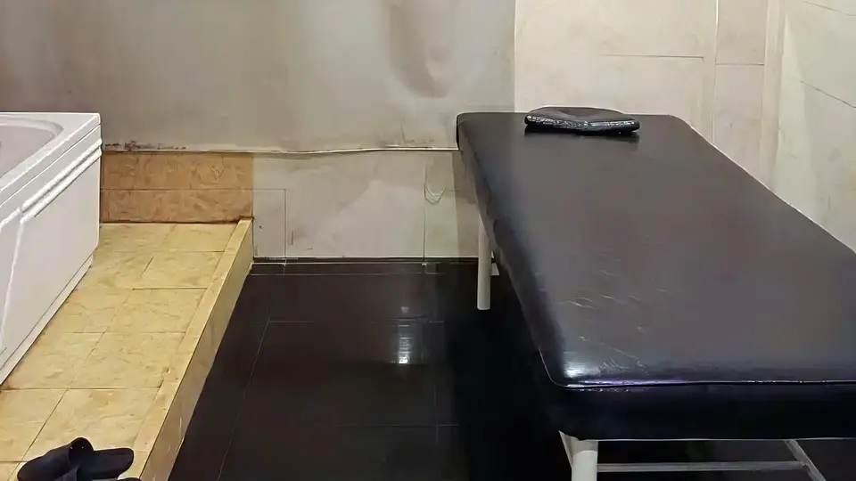 블랙 타일 바닥과 대형 욕조, 마사지 베드가 통합된 프리미엄 스파 룸