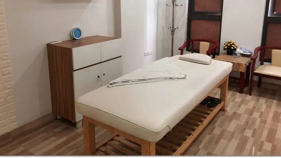수 사우나의 원목 바닥과 밝은 조명 아래 정갈하게 세팅된 마사지 베드와 수납장