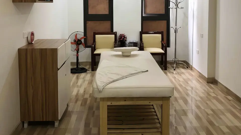 원목 바닥과 마사지 베드, 대기용 의자가 구비된 넓은 트리트먼트 룸