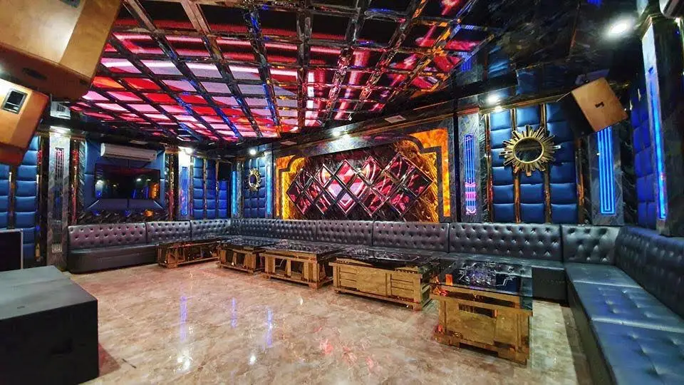 레드 LED 격자 천장과 블랙 가죽 소파, 골드 테이블이 길게 배치된 크라운 VIP 파티 룸