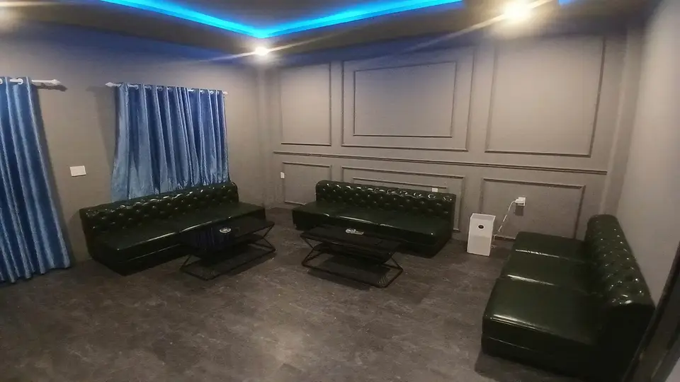 블루 간접 조명과 다크 그린 체스터필드 소파 3개가 배치된 넓은 VIP 전용 라운지 룸