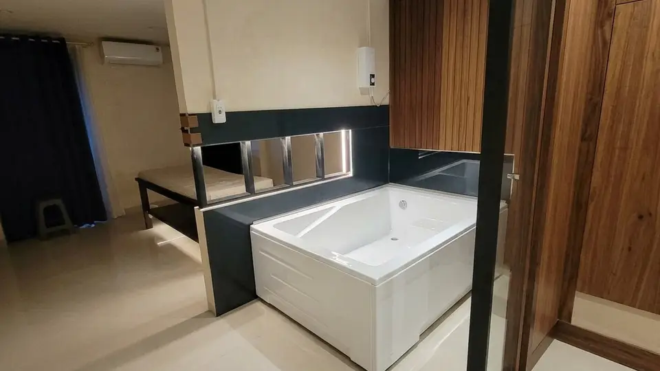 다크 타일과 목재 패널로 마감된 스파 룸 내부, 대형 백색 욕조와 마사지 베드가 배치된 모습